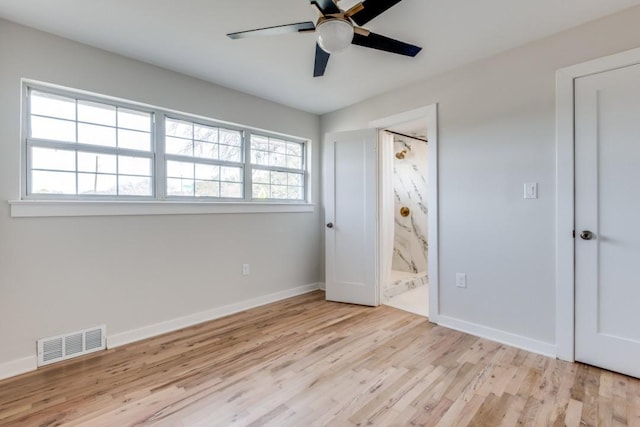 unfurnished bedroom featuring visible vents, ensuite bath, baseboards, and wood finished floors