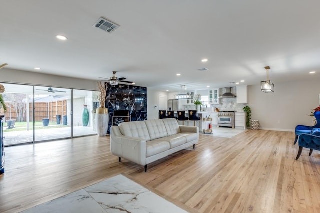 living room featuring a ceiling fan, light wood-type flooring, visible vents, and recessed lighting