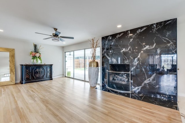 unfurnished living room featuring a ceiling fan, recessed lighting, a premium fireplace, and wood finished floors