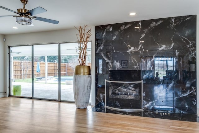 interior space with recessed lighting, ceiling fan, a premium fireplace, and wood finished floors