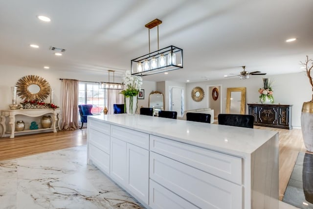 kitchen featuring marble finish floor, white cabinets, and recessed lighting