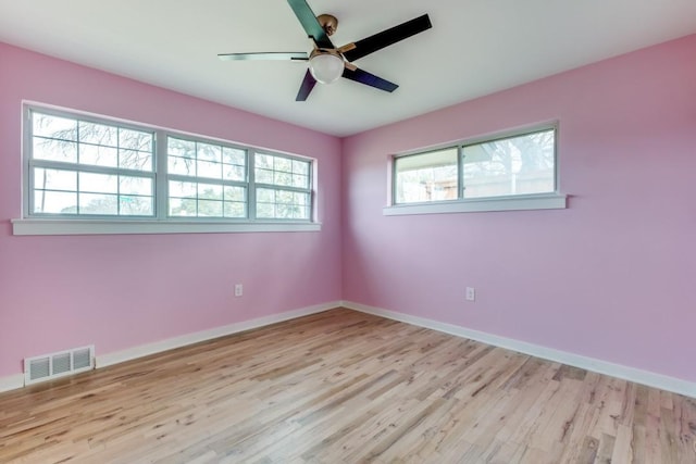 spare room featuring a ceiling fan, wood finished floors, visible vents, and baseboards