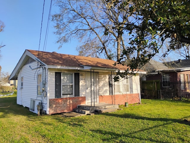 view of front facade featuring brick siding, a front yard, fence, and a shingled roof