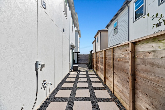 view of side of property featuring central AC, fence, and stucco siding