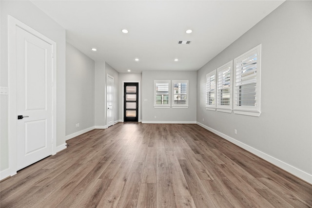 empty room featuring light wood-style floors, baseboards, visible vents, and recessed lighting