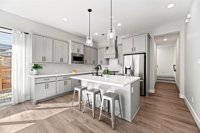 kitchen with stainless steel appliances, gray cabinets, light countertops, and light wood-style flooring