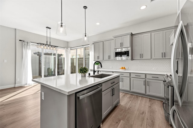 kitchen with stainless steel appliances, light wood-type flooring, a sink, and gray cabinetry