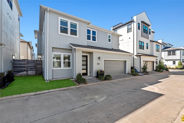 view of front of home with a garage, concrete driveway, a residential view, fence, and stucco siding