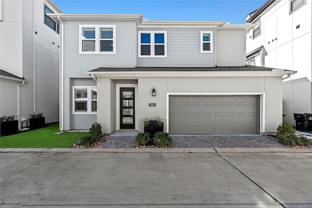 view of front facade with an attached garage, a shingled roof, decorative driveway, and stucco siding