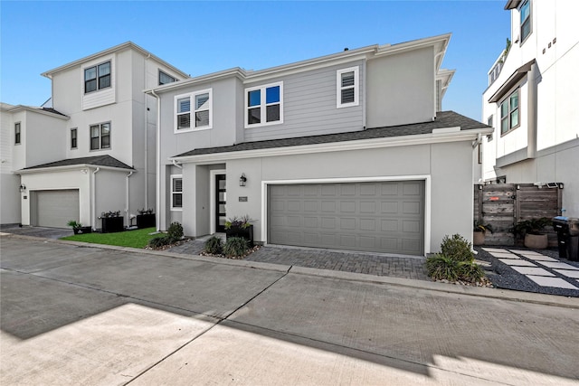 view of property featuring a garage, driveway, a shingled roof, and stucco siding