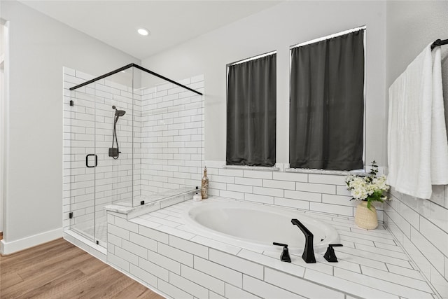 bathroom with baseboards, wood finished floors, a garden tub, a shower stall, and recessed lighting