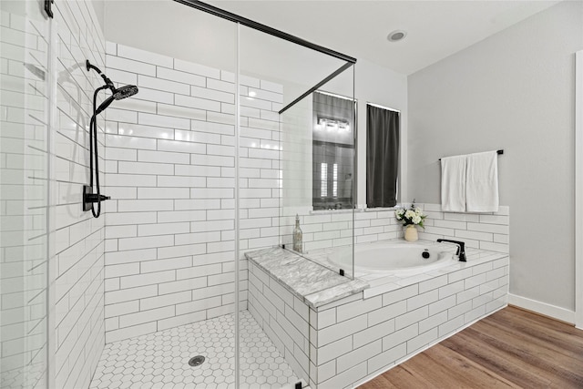 full bath featuring a garden tub, a shower stall, baseboards, and wood finished floors