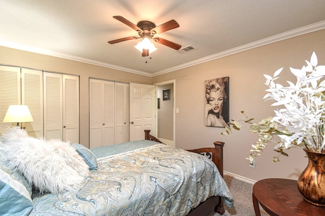 carpeted bedroom with multiple closets, visible vents, ornamental molding, ceiling fan, and baseboards