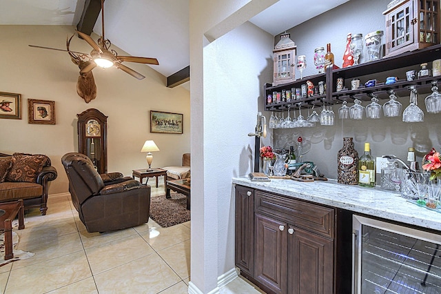 bar featuring ceiling fan, light tile patterned floors, vaulted ceiling with beams, beverage cooler, and a dry bar