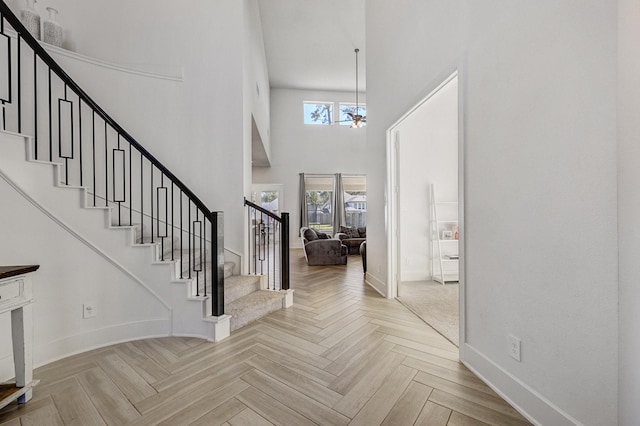 foyer entrance featuring stairway, baseboards, and a high ceiling