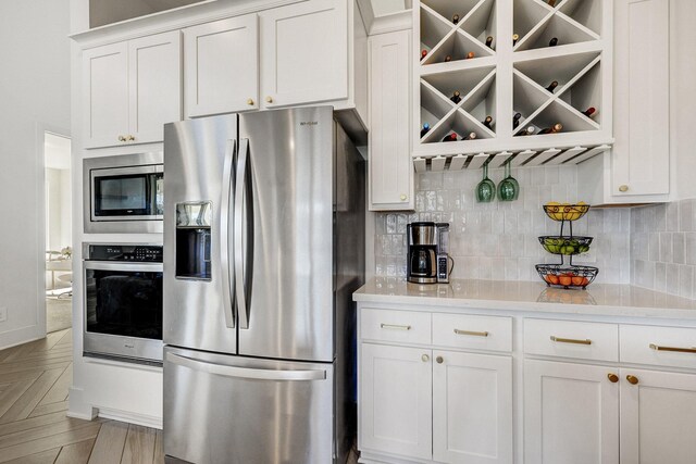 kitchen with tasteful backsplash, white cabinetry, and stainless steel appliances