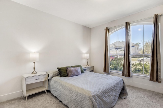 bedroom featuring baseboards, multiple windows, and light colored carpet