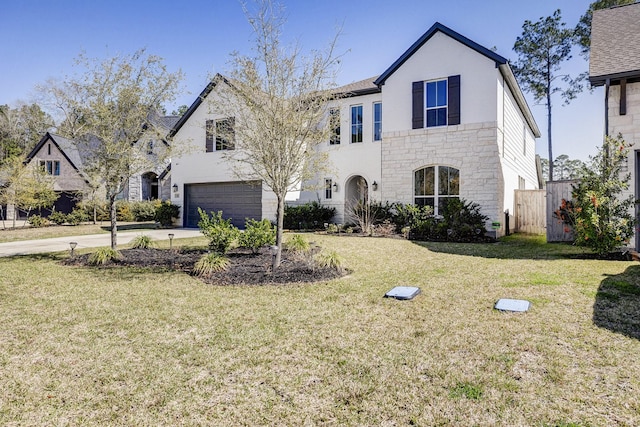 view of front of home featuring a garage, stone siding, a front yard, and driveway