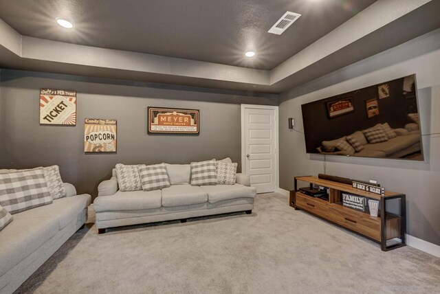 carpeted living area with a raised ceiling, recessed lighting, baseboards, and visible vents