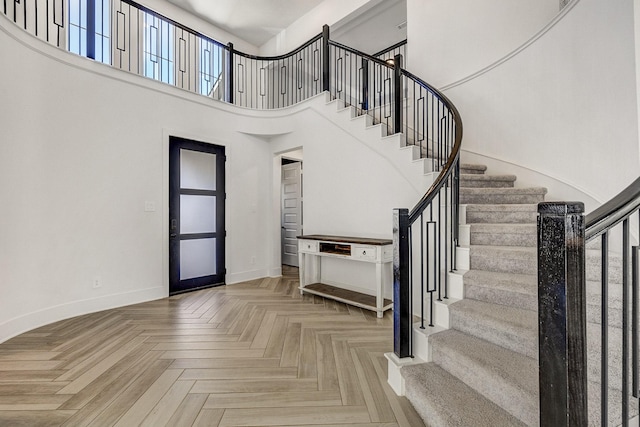 foyer featuring stairway, baseboards, and a towering ceiling