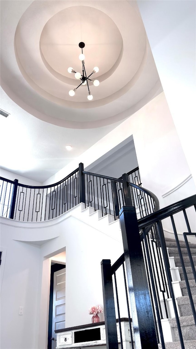 staircase with visible vents, a high ceiling, and a chandelier