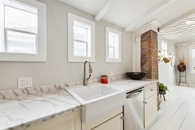 kitchen featuring baseboards, light wood-style flooring, a sink, stainless steel dishwasher, and beamed ceiling