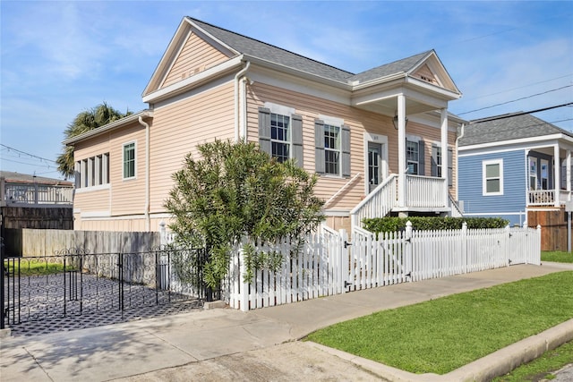 view of front facade with a fenced front yard, roof with shingles, and a gate