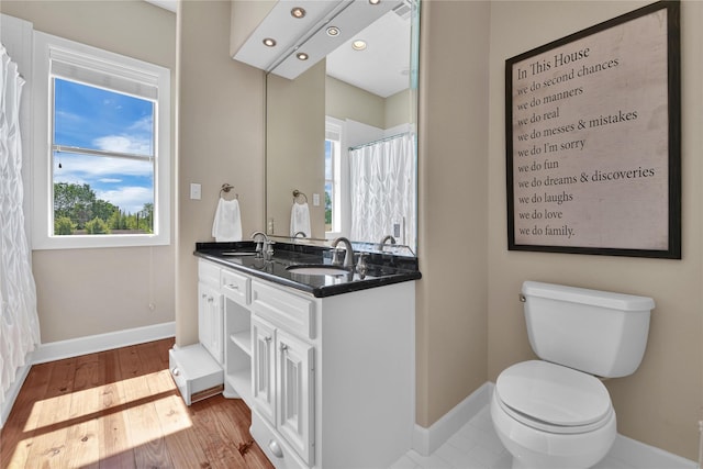 438 S Burnett Dr, Baytown, TX 77520 - bathroom featuring wood finished floors, a sink, toilet, and baseboards