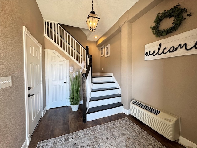 stairs with a notable chandelier, a textured wall, wood finished floors, and baseboards