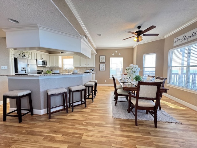 dining area featuring a wealth of natural light, light wood-type flooring, and a textured ceiling