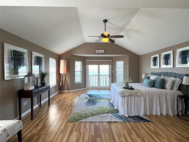 bedroom with access to outside, a textured ceiling, light wood-type flooring, lofted ceiling, and baseboards