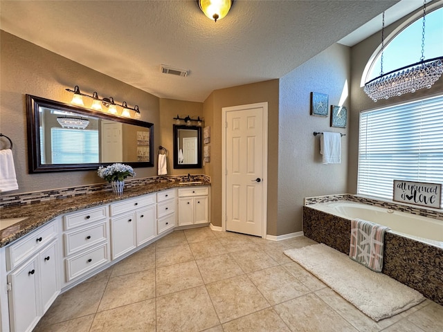 full bathroom with double vanity, an inviting chandelier, a textured wall, and a textured ceiling