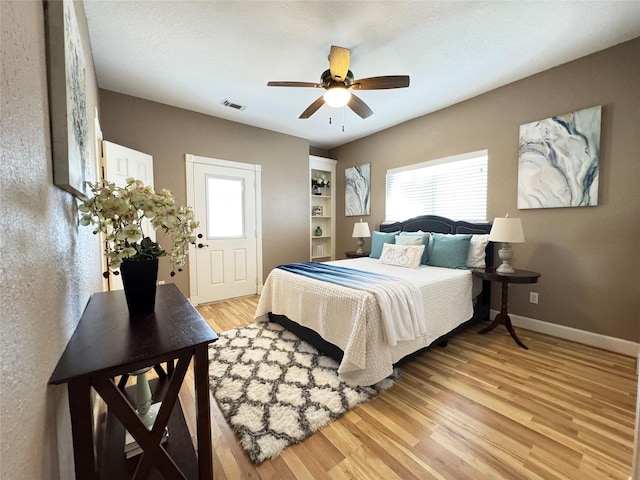 bedroom with light wood-style flooring, baseboards, multiple windows, and visible vents
