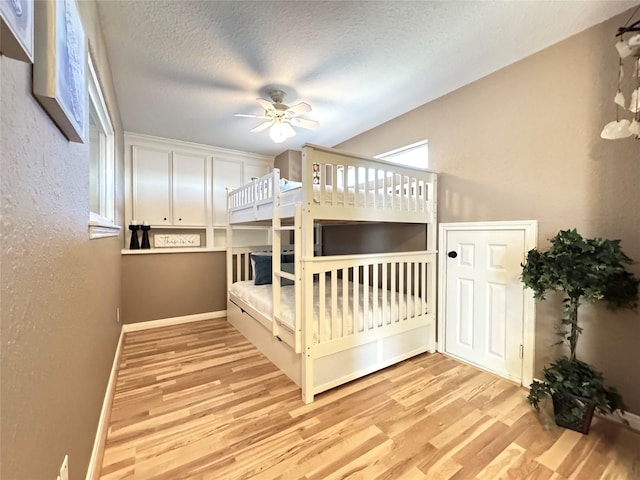 bedroom with baseboards, ceiling fan, wood finished floors, and a textured ceiling