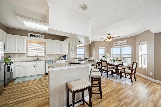 438 Jeanie Lynne Cir, Galveston, TX 77554 - kitchen with dishwasher, light wood finished floors, a breakfast bar, a kitchen island, and ornamental molding