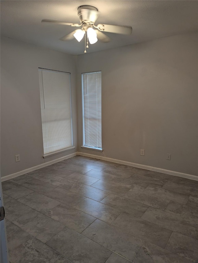 unfurnished room with a ceiling fan, a textured ceiling, and baseboards