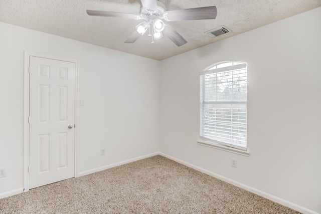 carpeted empty room with a textured ceiling, ceiling fan, visible vents, and baseboards