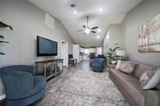 living area with high vaulted ceiling, ceiling fan, visible vents, and wood finished floors