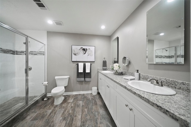 bathroom with a stall shower, a sink, toilet, and wood finished floors