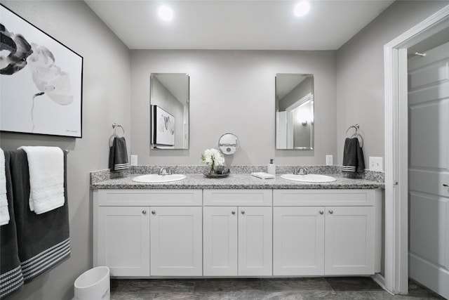 bathroom featuring double vanity, a sink, and recessed lighting