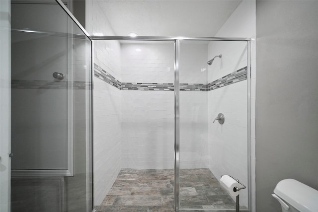 full bathroom featuring a stall shower and toilet