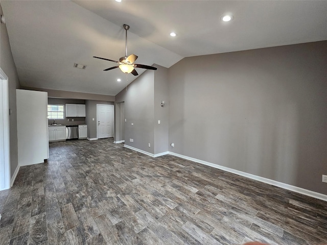 unfurnished living room featuring ceiling fan, a sink, visible vents, vaulted ceiling, and dark wood-style floors