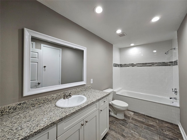 bathroom with toilet, recessed lighting, tiled shower / bath combo, vanity, and visible vents