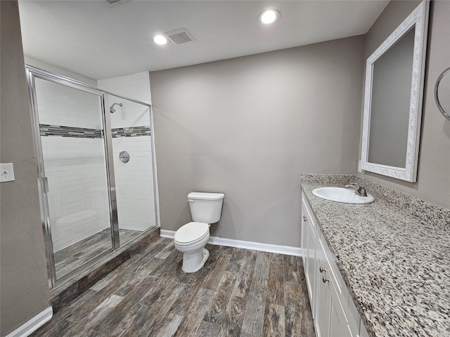 bathroom with toilet, wood finished floors, visible vents, baseboards, and a shower stall