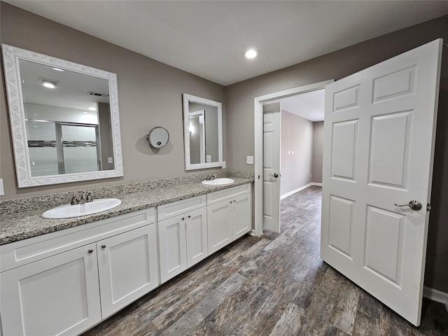 full bath featuring double vanity, a stall shower, a sink, and wood finished floors