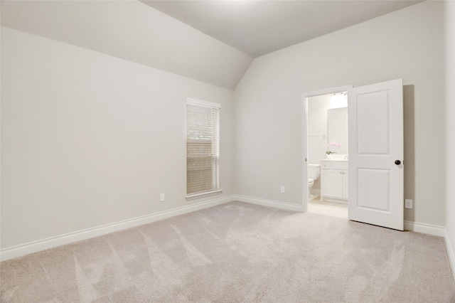 empty room with vaulted ceiling, baseboards, and light colored carpet