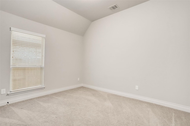 carpeted spare room with lofted ceiling, visible vents, and baseboards