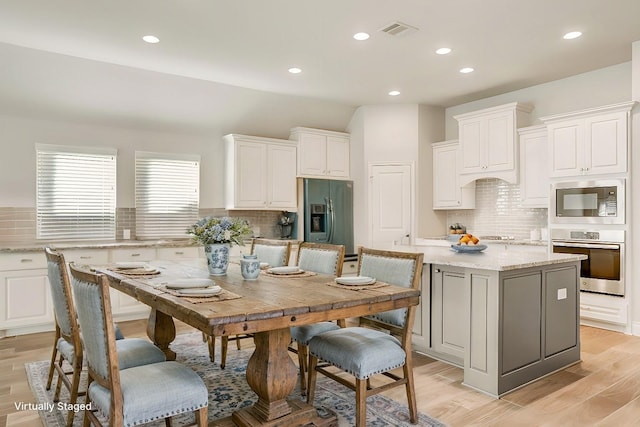 kitchen with light wood-style flooring, visible vents, white cabinets, appliances with stainless steel finishes, and a center island