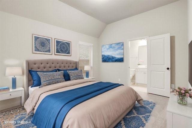 bedroom with vaulted ceiling, connected bathroom, and light colored carpet