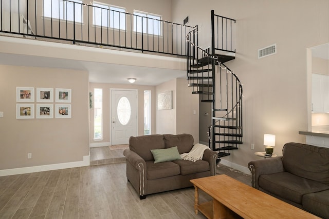 living room with visible vents, stairway, a high ceiling, wood finished floors, and baseboards